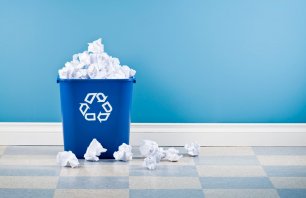 Blue plastice recycling container full of crumpled paper.